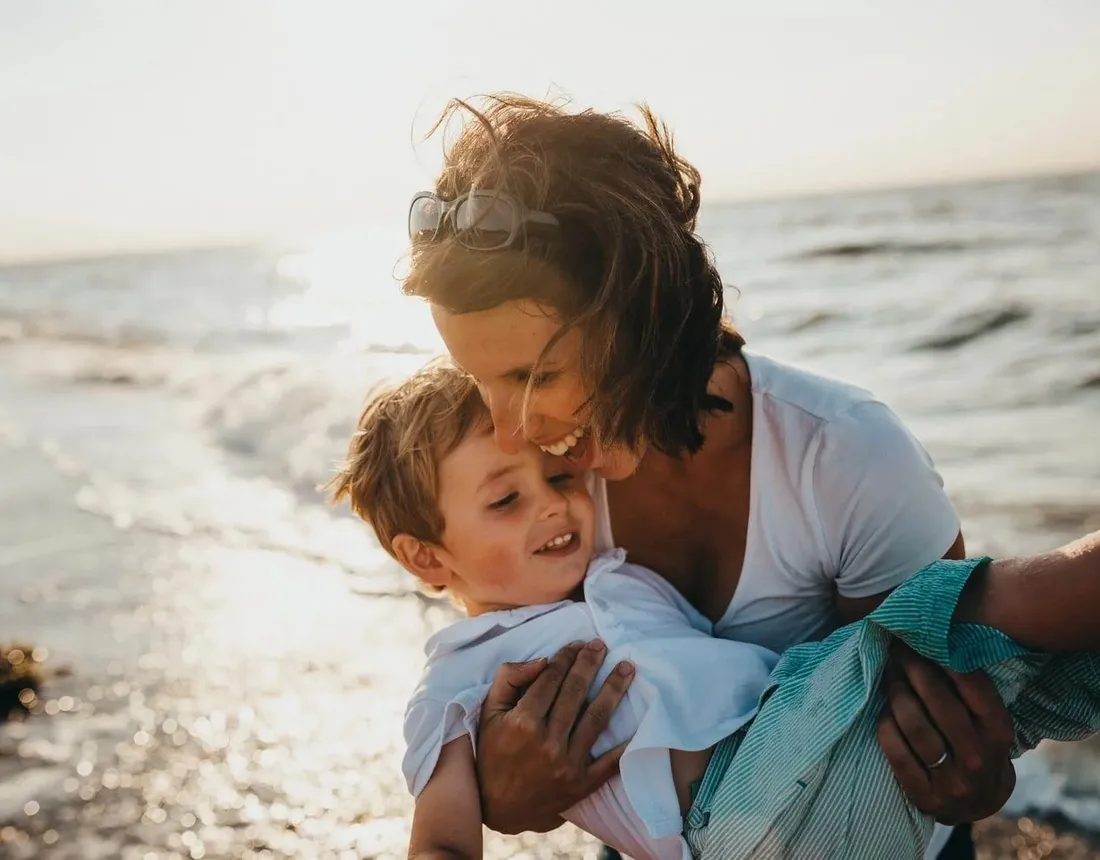 A parent and child laughing together at the beach