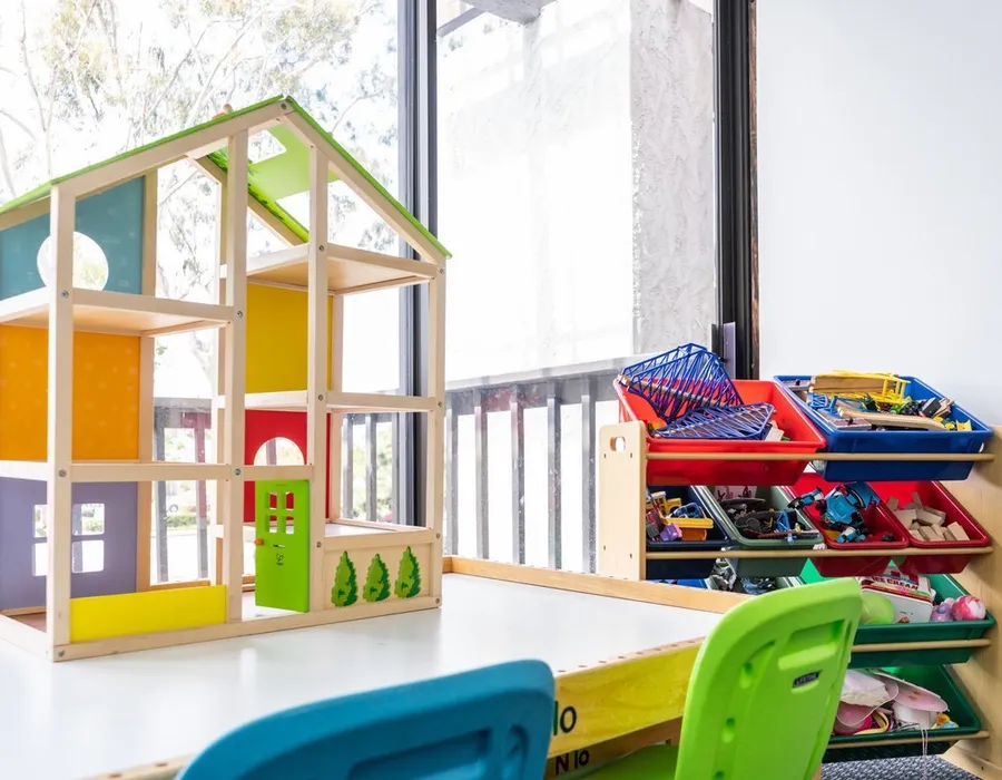 A bright play-therapy room at Insight with a wooden dollhouse and toy shelves