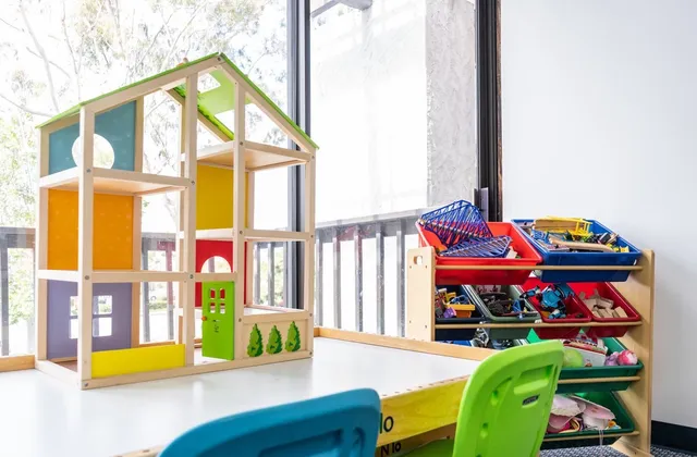 A bright play-therapy room at Insight with a wooden dollhouse and toy shelves