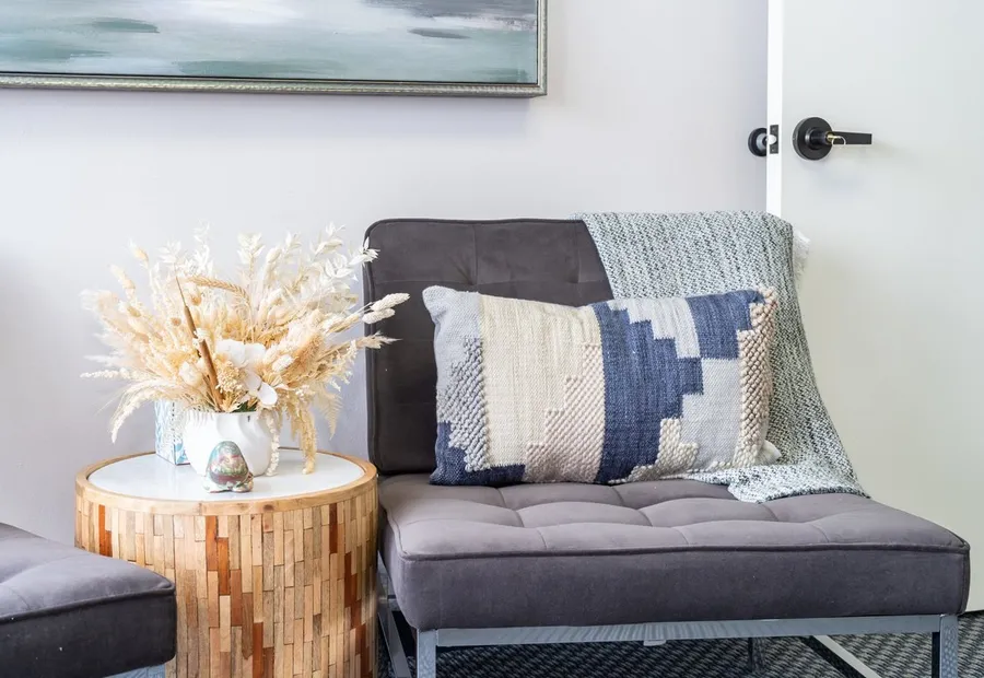 Grey sofa with patterned pillows beside a wood side table