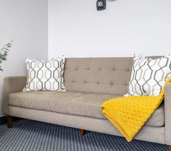 A therapy room with a beige sofa and a yellow throw
