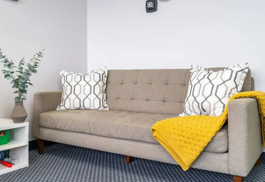 Beige sofa with a yellow throw in a therapy room