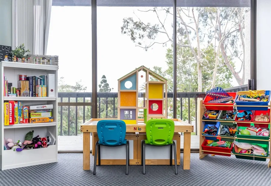 Play room with bookshelves, small tables and a view of the trees