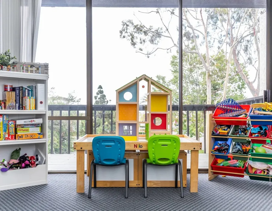 A sunny classroom-style play area at Insight with small tables and toy shelves