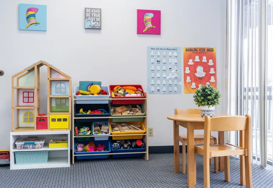 Play area with a dollhouse, toy bins and a child-sized table