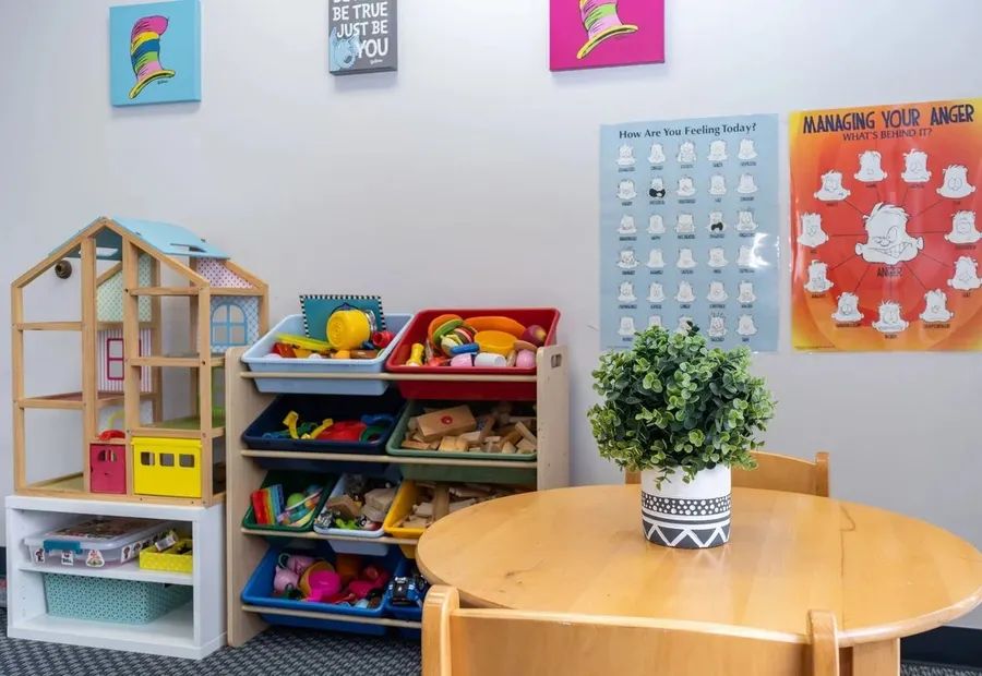 Round wooden table and toy shelves with feelings posters on the wall