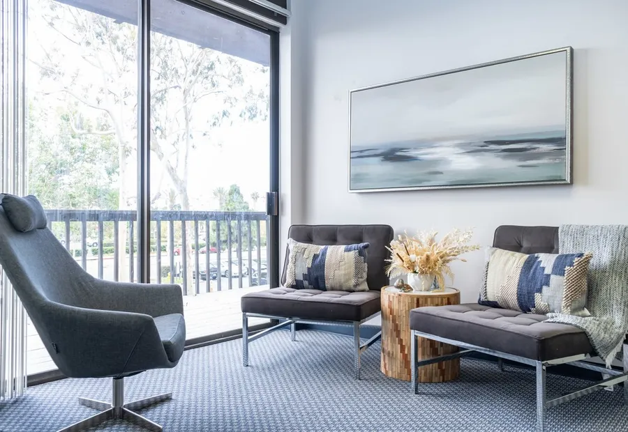 Waiting area with armchairs, calm artwork and a view of the trees