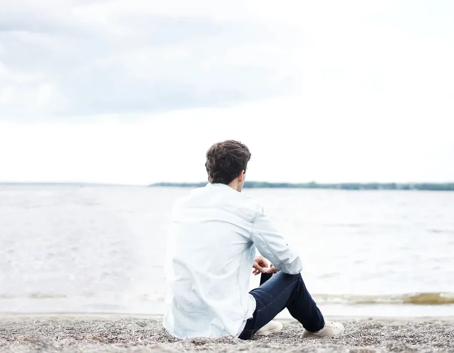 A teenager sitting quietly by the water